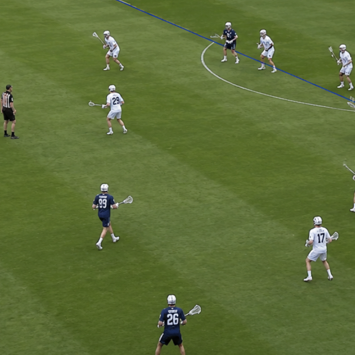 Lacrosse match in progress with players on a field